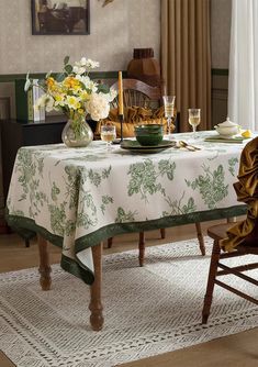 a dining room table is set with flowers and plates on it, along with two chairs