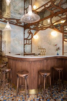 a bar with three stools in front of it and lights hanging from the ceiling