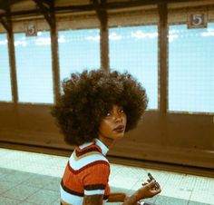 a woman with an afro writing on a piece of paper in front of a window