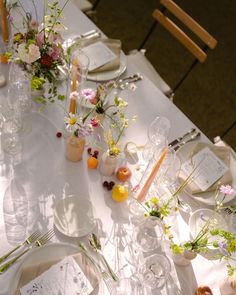 the table is set with flowers, candles and place settings for guests to sit at