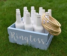 a bunch of white bottles in a crate on the grass with rope wrapped around them