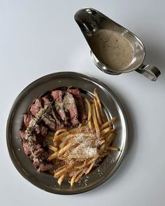 steak and french fries on a plate with gravy in a saucer next to it