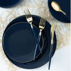 two forks and one knife on a blue plate with gold trimmings, next to another set of silverware