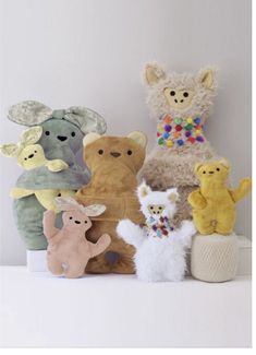 a group of stuffed animals sitting next to each other on a white shelf in front of a wall