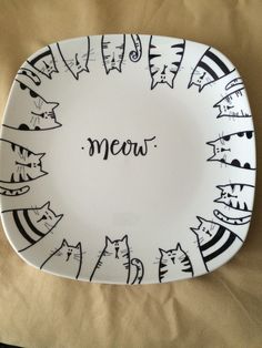 a white plate with cats drawn on it and the word meow written in black