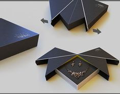 three black boxes with jewelry in them and an arrow pointing to the top one that is open