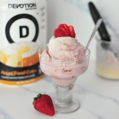 a bowl of ice cream with strawberries in it next to a bottle of d lemonade