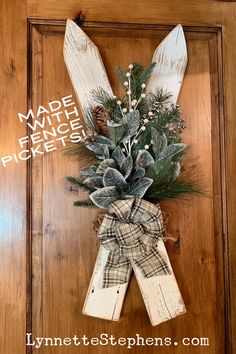 a door hanger decorated with pine cones, evergreens and plaid ribbon tied to it