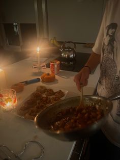 a person cooking food in a pan on a table with candles and tea light holders