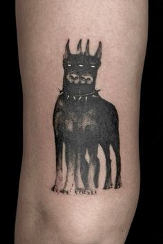 a black cat tattoo on the right side of the leg, with two smaller cats behind it