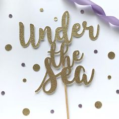 a cake topper that says under the sea with confetti and streamers