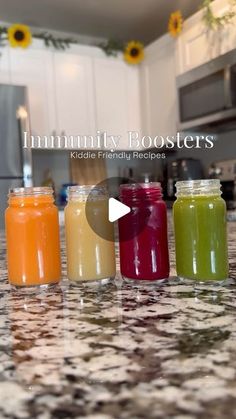 four jars filled with different colored drinks on top of a counter