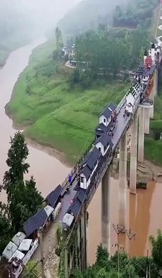 a train crossing over a bridge in the middle of a river with cars on it