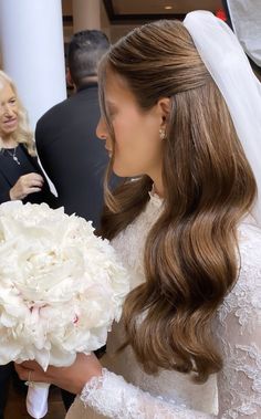 a woman holding a bouquet of white flowers in her right hand and wearing a veil