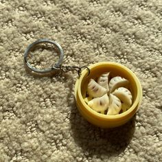 a small yellow bowl filled with food on top of a carpeted floor next to a metal keychain