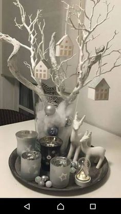 a glass vase filled with candles on top of a table next to a tree and other decorations