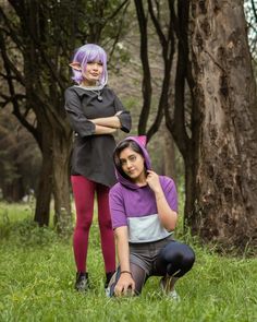 two young women are posing in the grass