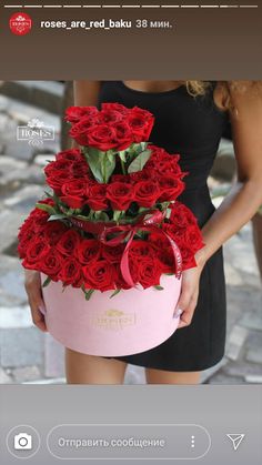 a woman holding a pink box filled with red roses