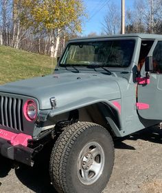 a gray jeep with pink trim parked in a parking lot