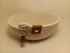 a white woven basket with brown leather tassels