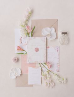 the wedding stationery is laid out on top of each other with flowers and paper