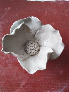 a white flower shaped bowl sitting on top of a red rug