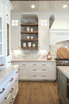 a kitchen with white cabinets and wood floors