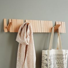 two bags are hanging on the wall next to a coat rack and scarf hanger