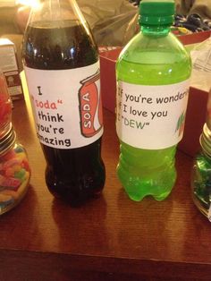 two soda bottles with candy in them sitting on a table next to other drinks and candies