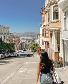 San Francisco painted ladies, antique buildings along the street facing a slanted hill. There’s a view of the city scape and a girl walking down the hill with the picture taken from her back. She has long black hair, jeans, and a trader joes tote bag. Sanfransisco Street Aesthetic, San Francisco Spring Break, Cute Outfits For San Francisco, Traveling To San Francisco, Sf Instagram Pictures, San Francisco Astethic, San Francisco Aesthetic Photos, Apartment In San Francisco, Life In San Francisco