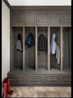 a coat rack with several coats hanging from it's sides and two red boots on the floor