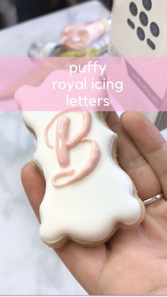 a hand holding a decorated cookie with the letter e on it's front and side