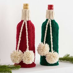 two knitted wine bottles with pom - poms on the top and bottom