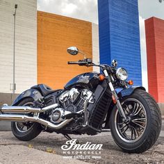 a black motorcycle parked in front of a building with multicolored walls behind it