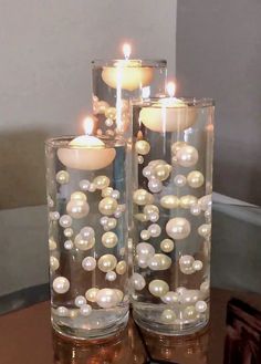 two glass vases with pearls and candles in them