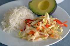 a white plate topped with rice and veggies next to an avocado