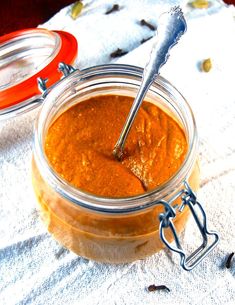 a jar filled with peanut butter sitting on top of a white towel next to a spoon