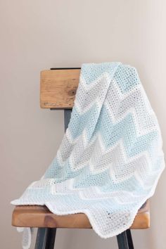 a white and blue blanket sitting on top of a wooden chair