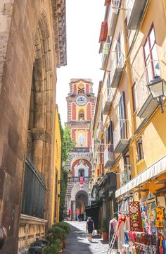 an alley way with shops and people walking down the street in front of buildings on either side