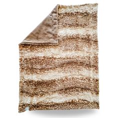 the brown and white blanket is folded on top of an animal - print material sheet