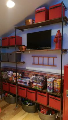 a television is mounted on the wall above some shelves with bins and baskets in front of it