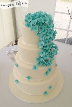 a white wedding cake with blue flowers on top