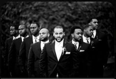 a group of men standing next to each other wearing suits and ties with one man in the middle