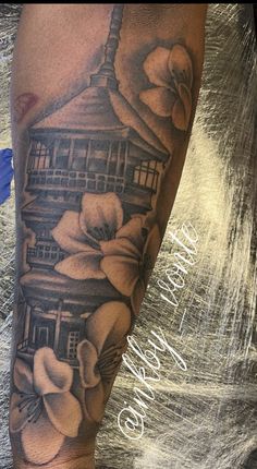 a person with a tattoo on their leg that has flowers and a building in the background