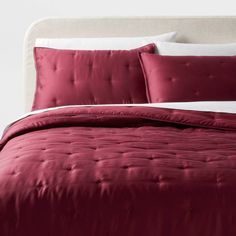 a bed with a red comforter and pillows