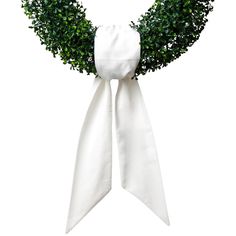 a white ribbon tied around a wreath with green leaves on it's end and the top knoted off