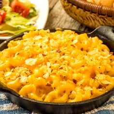 a skillet filled with macaroni and cheese sitting on top of a table