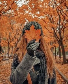 a woman holding an orange leaf in front of her face