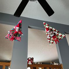 three christmas decorations hanging from the ceiling in a room with two mirrors and a fan