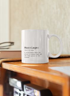 a white coffee mug sitting on top of a wooden table next to a pile of books